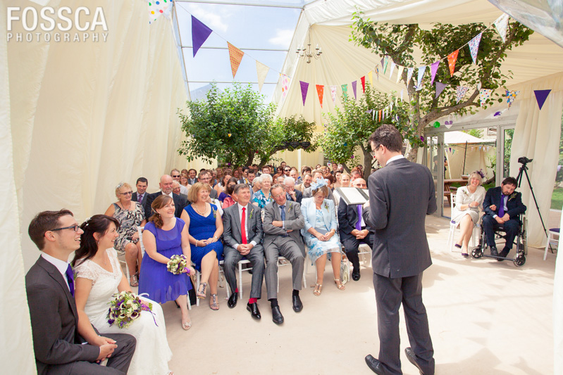 Bride, groom and wedding guests laugh while Ewan conducts the wedding ceremony