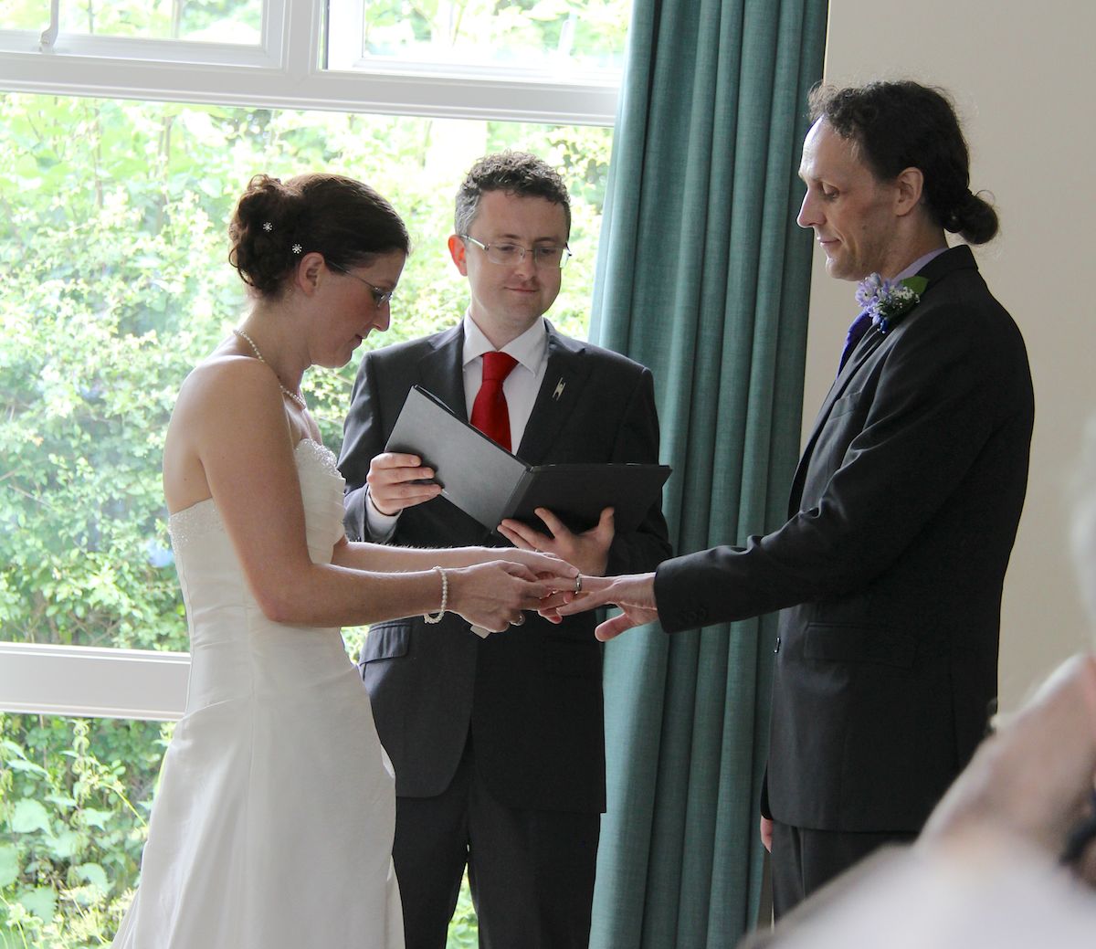 Bride and groom exchange rings while Ewan watches