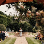 Outdoor ornamental garden ceremony seen through flower arch.