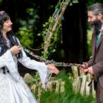 A bride and groom tying the knot as they tie part in a hand fasting ceremony in an outdoor Humanist wedding in Wiltshire