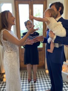 Humanist celebrant Jenny Ashley conducts a ceremony as a baby is passed from groom to bride. Big smiles all round.