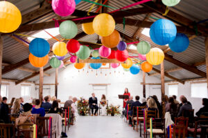 A wedding ceremony at White Syke Fields barn, decorated with colourful lanterns.