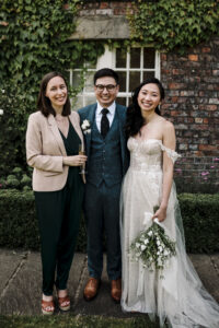 A celebrant stands with a newly married couple outside Grays Court in York.