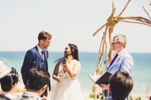 Simon with Bride and Groom, who are looking at each other.