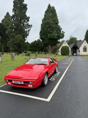 Red Lotus Excel parked in a cemetery